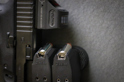 A pistol and two 9mm magazines held by a CoJo gun gripper gun magnet.