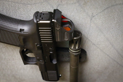 Pistol and the end of a barrel of a rifle being held by a CoJo Gun gripper gun magnet