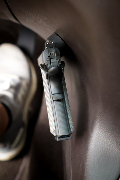 Picture of a Semi Automatic pistol from behind mounted on the side of the console of a vehicle.